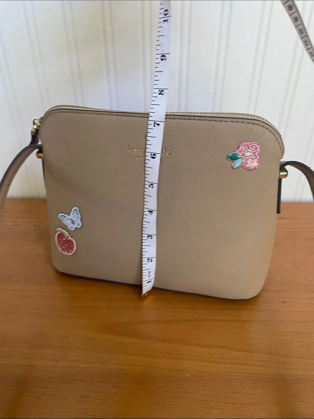 Kate Spade tan crossbody with floral, butterfly and fruit accents